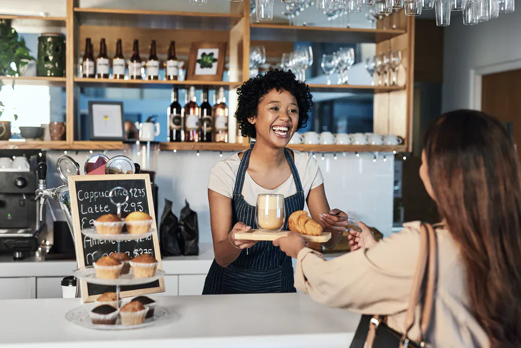 serveuse souriante servant un client dans un coffee shop illustrant une expérience inclusive et une offre adaptée à tous les profils
