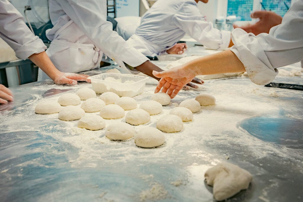 Team of pastry chefs shaping dough in a lab, illustrating coffee shop production and recipe reformulation