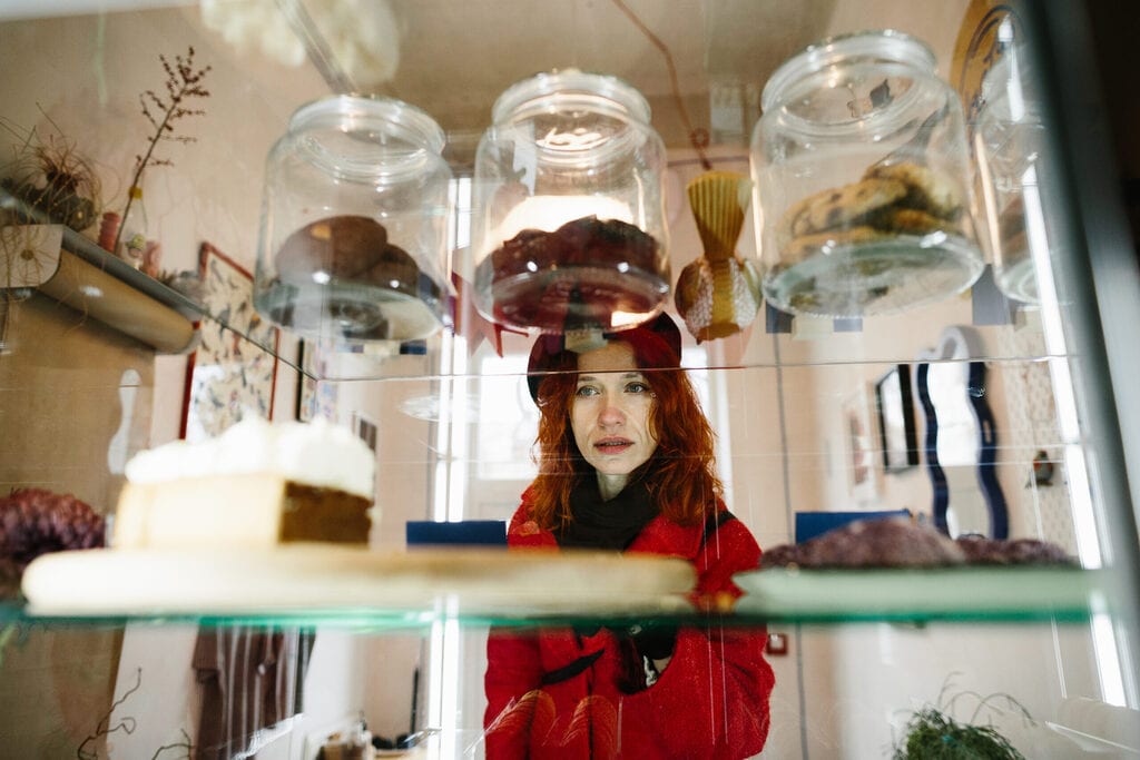 cliente face à une vitrine de pâtisserie en coffee shop illustrant le choix difficile lié aux contraintes alimentaires et à une offre peu adaptée